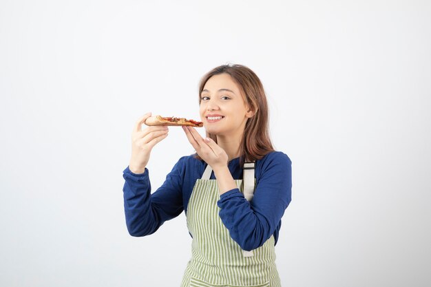 Retrato de mujer cocinera en delantal sosteniendo pizza y sonriendo