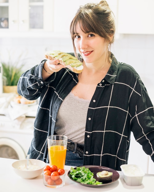 Retrato de una mujer comiendo pan con aguacate