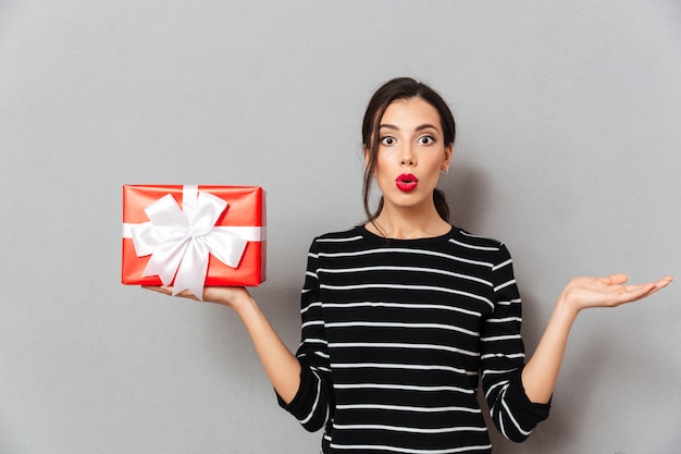 Retrato de una mujer confundida con caja de regalo