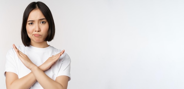 Retrato de una mujer coreana asiática que muestra un gesto de prohibición de parada que muestra el signo de la cruz del brazo de pie en t