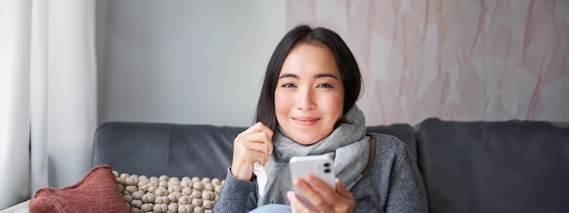 Foto gratuita retrato de una mujer coreana se siente enferma sosteniendo un teléfono inteligente llamando al médico de cabecera para que le atrapen la prescripción