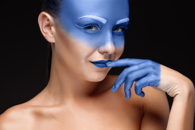 Retrato de una mujer cubierta con maquillaje artístico azul