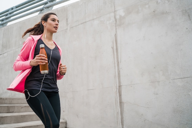 Retrato de una mujer deportiva corriendo en las escaleras al aire libre. Conceptos de fitness, deporte y estilo de vida saludable.