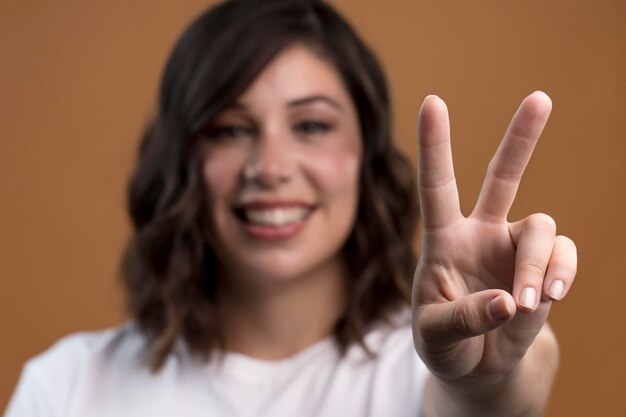 Retrato de mujer desenfocada mostrando el signo de la paz