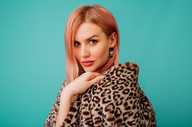 Retrato de mujer deslumbrante con cabello rosado en elegante abrigo esponjoso de invierno con estampado de leopardo