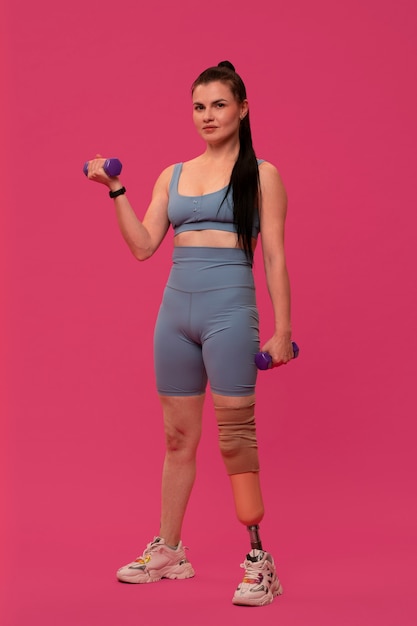 Foto gratuita retrato de mujer discapacitada con pierna protésica haciendo ejercicio con pesas