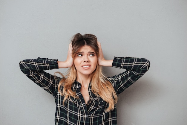 Foto gratuita retrato de una mujer disgustada cubriendo sus oídos con las manos