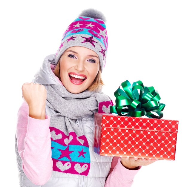 Retrato de mujer divertida con un regalo en una ropa de abrigo de invierno aislado en blanco