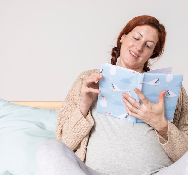 Retrato mujer embarazada leyendo libros de bebé