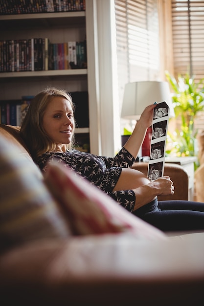 Foto gratuita retrato de mujer embarazada mirando una ecografía en la sala de estar