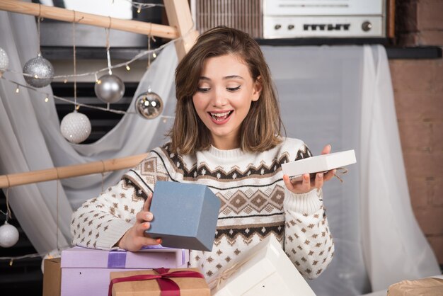 Retrato de una mujer emocionada abriendo el regalo de Navidad.