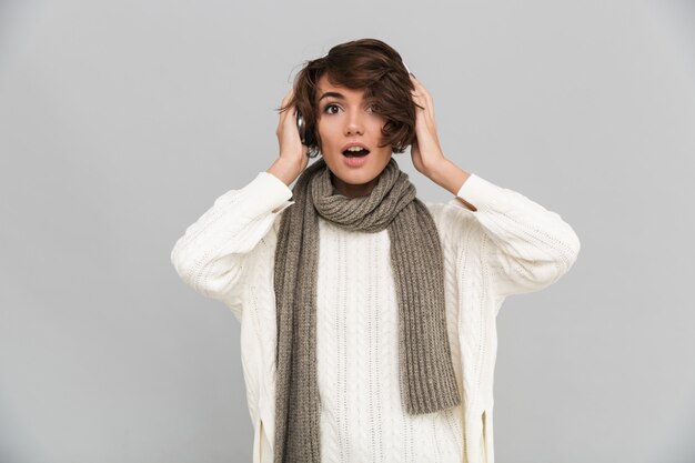 Retrato de una mujer emocionada en bufanda escuchando música