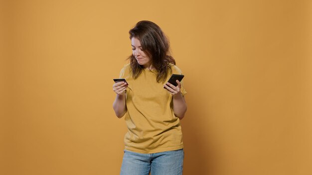 Retrato de una mujer emocionada por las compras en línea sosteniendo un teléfono inteligente escribiendo los detalles de la tarjeta de crédito haciendo la compra. Genial joven que pide productos casualmente usando el teléfono móvil para la entrega a domicilio.