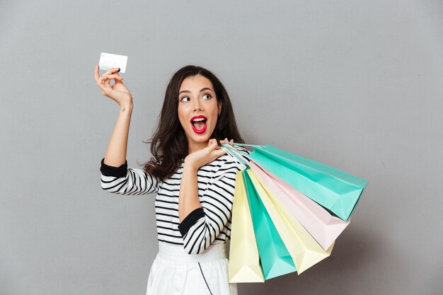 Retrato de una mujer emocionada mostrando tarjeta de crédito