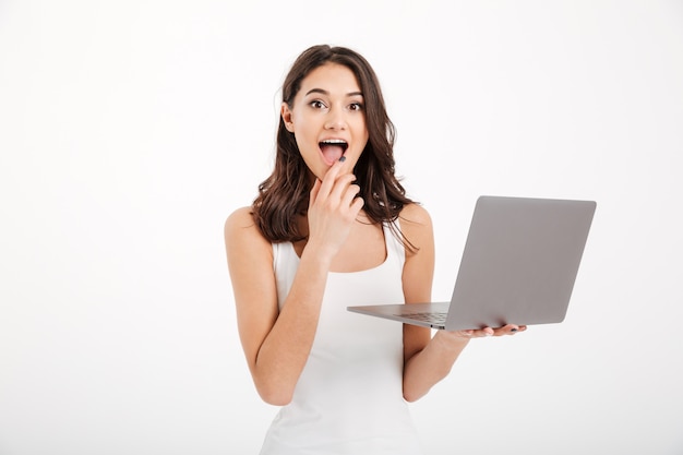 Retrato de una mujer emocionada vestida con una camiseta sin mangas usando laptop