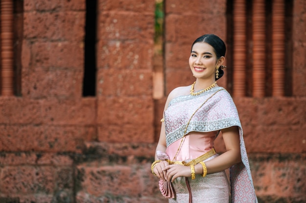 Retrato de mujer encantadora asiática vistiendo un hermoso vestido típico tailandés identidad cultura de Tailandia en el templo antiguo o lugar famoso con pose graciosamente