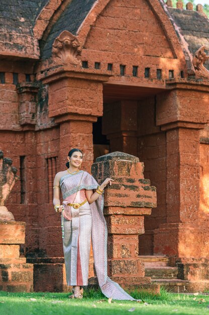 Retrato de mujer encantadora asiática vistiendo un hermoso vestido típico tailandés identidad cultura de Tailandia en el templo antiguo o lugar famoso con pose graciosamente