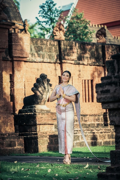 Retrato de mujer encantadora asiática vistiendo un hermoso vestido típico tailandés identidad cultura de Tailandia en el templo antiguo o lugar famoso con pose graciosamente