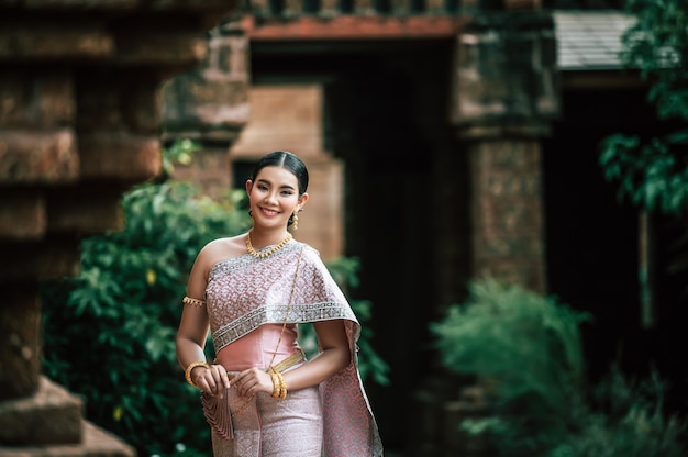 Retrato de mujer encantadora asiática vistiendo un hermoso vestido típico tailandés identidad cultura de tailandia en el templo antiguo o lugar famoso con pose graciosamente