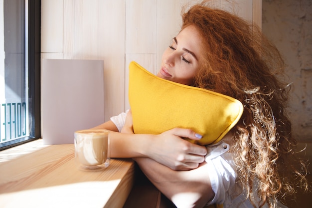 Retrato de una mujer encantadora joven pelirroja abrazando la almohada