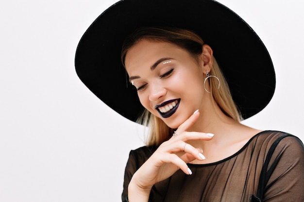 Retrato de mujer encantadora sonriente con lápiz labial negro y sombrero negro