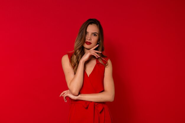 Retrato de mujer encantadora sonriente en vestido rojo posando