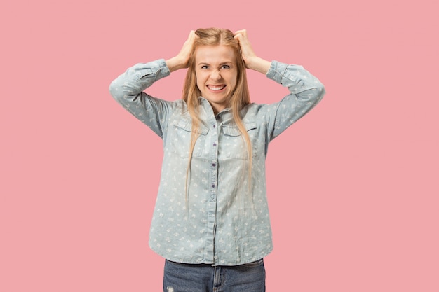 Retrato de una mujer enojada mirando a cámara aislada sobre un fondo rosa