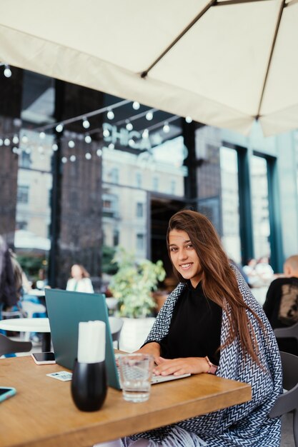 Retrato de mujer estudiante con net-book mientras está sentado en el café