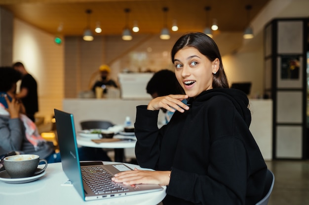 Retrato de mujer estudiante con netbook mientras está sentado en el café