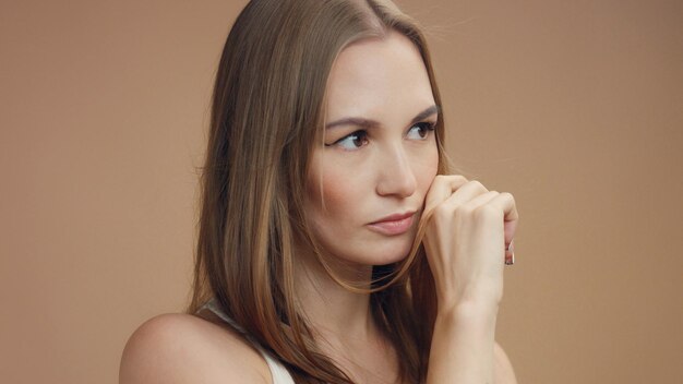 Retrato de mujer en estudio en tonos beige mujer rubia con pelo largo y recto