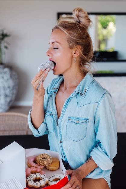 Foto gratuita retrato de mujer europea con cabello rubio disfrutando de donuts en la cocina en casa villa.