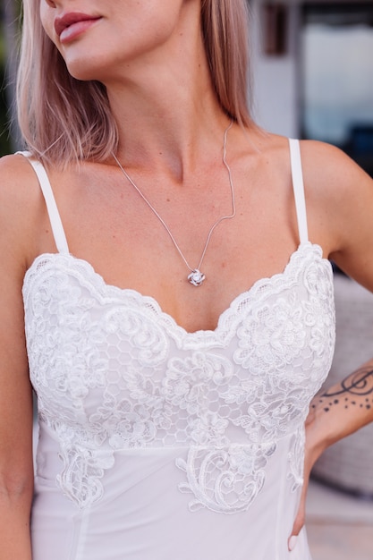 Retrato de mujer europea en vestido de novia con collar y anillo.