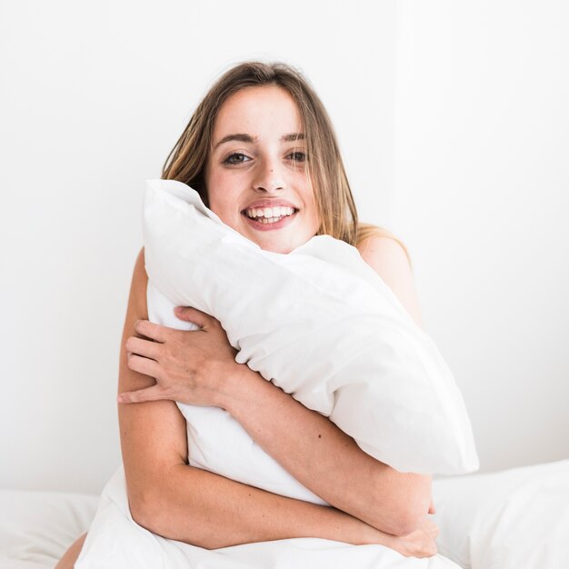 Retrato de una mujer feliz abrazando la almohada