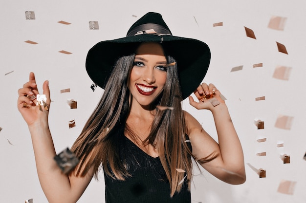 Retrato de una mujer feliz bailando emocionada en traje de halloween posando sobre murciélagos y pared de confeti. Fiesta de Halloween, verdaderas emociones felices