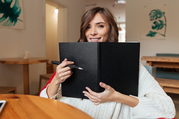 Retrato de una mujer feliz con bloc de notas de portada en blanco