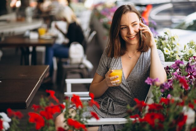 Retrato de una mujer feliz en un café con teléfono y jugo