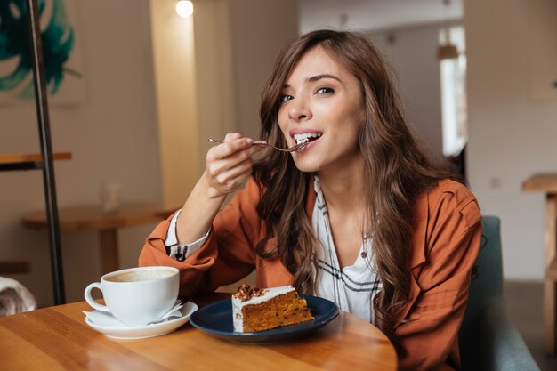 Retrato de una mujer feliz comiendo un pedazo de pastel