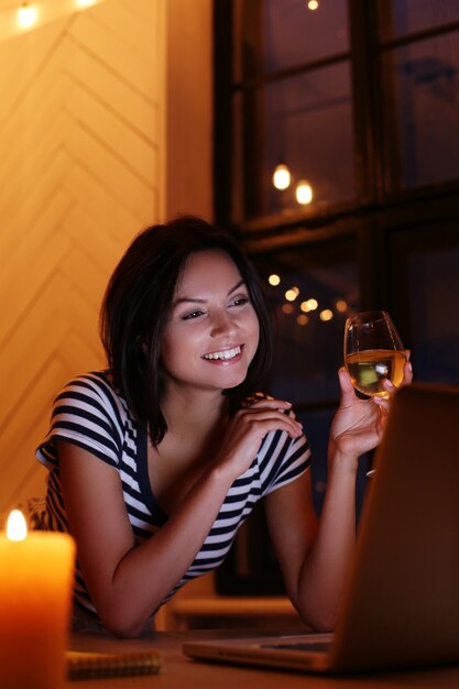 Retrato de mujer feliz con copa de vino mirando la pantalla de la pc