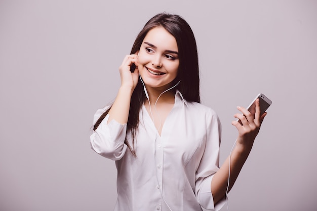 Retrato de una mujer feliz escuchando música en auriculares aislado sobre un fondo blanco.