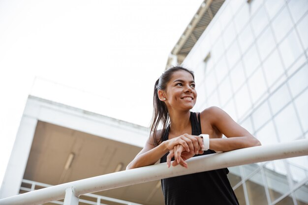 Retrato de una mujer feliz fitness apoyándose en un riel