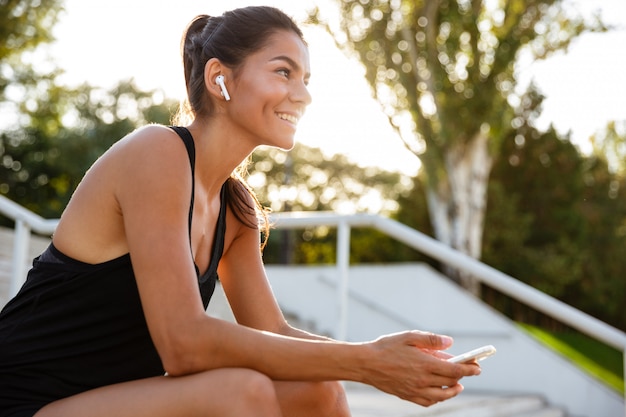 Retrato de una mujer feliz fitness en auriculares