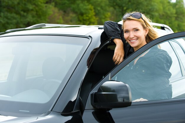 Retrato de mujer feliz joven atractiva en el coche nuevo - al aire libre