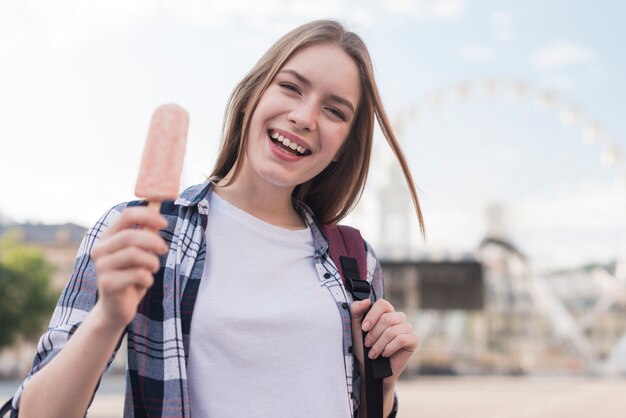 Retrato de la mujer feliz joven que sostiene el polo en el parque de atracciones