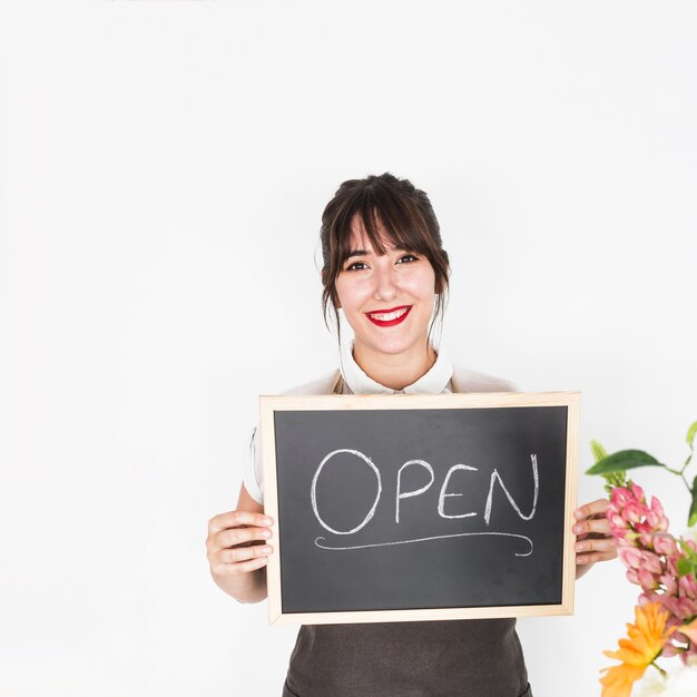 Retrato de una mujer feliz mostrando pizarra con palabra abierta