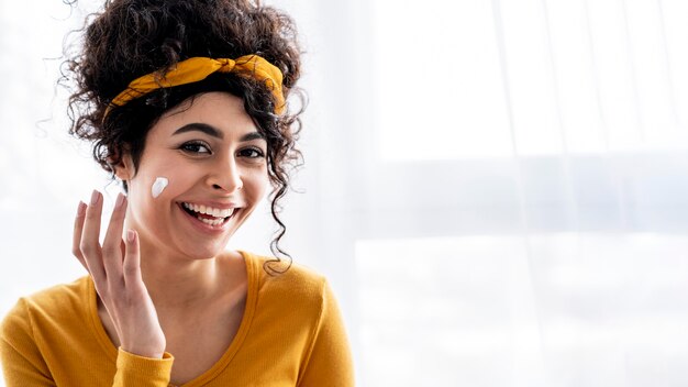 Retrato de mujer feliz riendo y jugando con crema hidratante con espacio de copia