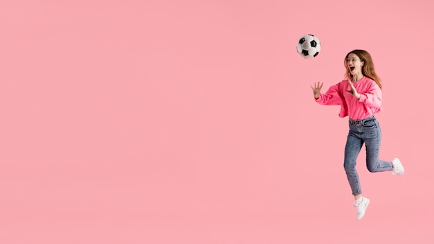 Foto gratuita retrato mujer feliz saltando con pelota de fútbol