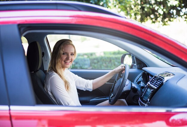 Retrato de una mujer feliz sentada dentro de coche