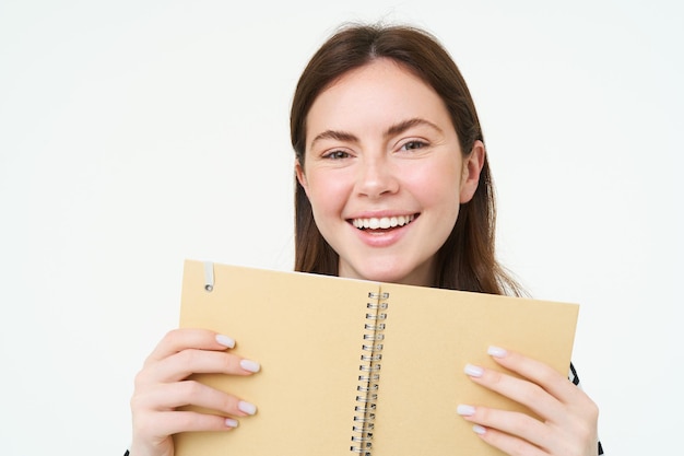 Foto gratuita retrato de una mujer feliz sonriendo mostrando su libro planificador diario sosteniendo un cuaderno planificando su viaje un