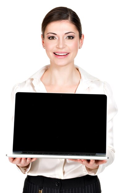 El retrato de la mujer feliz sonriente sostiene la computadora portátil en la palma con la pantalla en blanco - aislada en blanco. Comunicación conceptual.