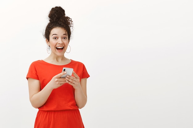 Retrato de mujer feliz sorprendida emocionada con el pelo rizado en vestido rojo